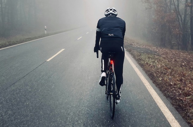 ciclista entre la niebla en un día de invierno con chaqueta y frío